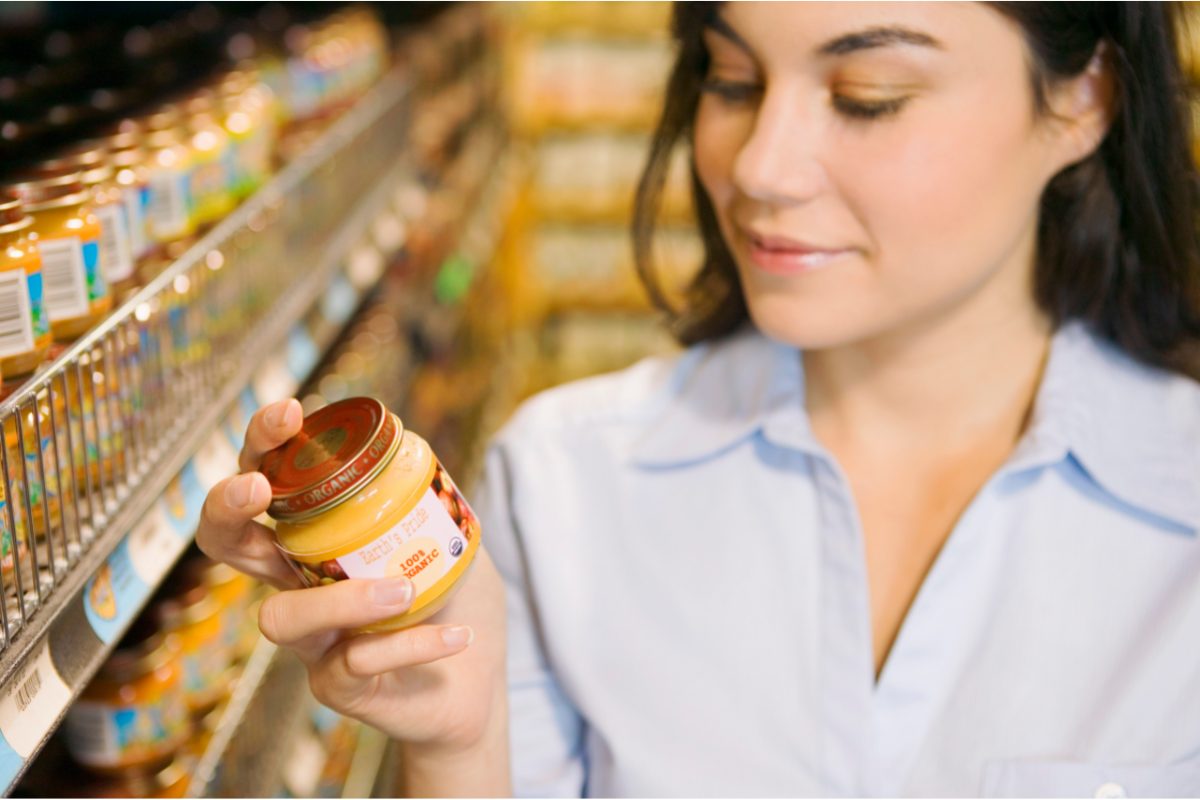 Mulher observando rótulo e etiqueta de um produto no mercado